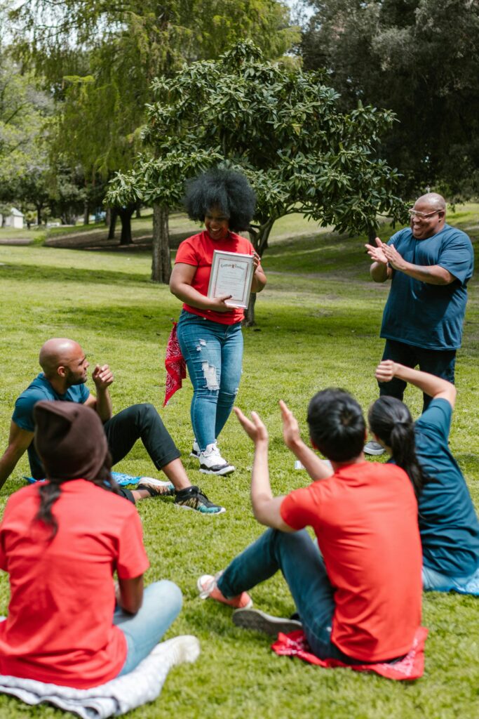 zipwp image 7551451 A group of adults celebrating an award outdoors in a park setting.